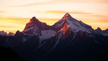 Towering mountains with snowy peaks bathed in the warm light of sunrise, casting long shadows and illuminating the sky with hues of pink, orange, and gold. photo