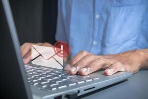 Man working on laptop with email spam notification alert with warning caution photo
