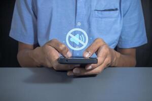 Man holding a mobile phone with mute sound or silent mode symbol photo