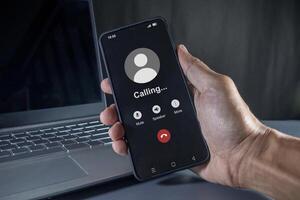 Hand holding a mobile phone with outgoing call screen. Call someone with a voice call. photo