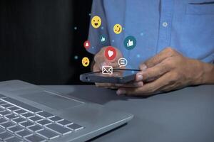 Man holding a smartphone to open social media applications. Chat with friends and send emotion icons. photo