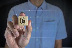Man holding a wooden block with shield protect icon on virtual screen. Information and cyber security or personal data protection concept. photo