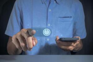 Man pressing power button on virtual screen to turn on or off a smartphone photo