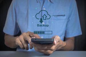Phone data backup and cloud data storage concept. Man using a smartphone to upload data to cloud storage. photo
