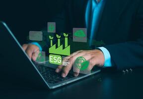 Businessman using laptops to analyze ESG on screen in business investment strategy concept, ESG environment social governance investment business concept, Environmental and business growth together. photo