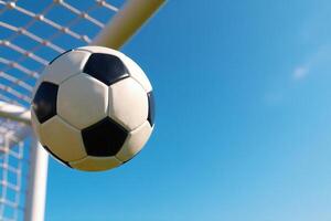 Soccer Ball Flying into Goal Net Against Blue Sky photo