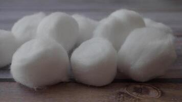 Soft and fluffy cotton balls placed on a rustic wooden background, creating a warm vibe video