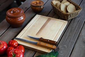 Top-down view, variety of fresh tomatoes and cucumbers next to a wooden cutting board with two knives. Clay pot, adding to the rustic vibe. photo