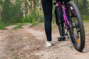 Bicycle parked on a forest trail, suggesting a perfect setting for mountain biking. The trail winds through dense trees, providing a scenic and adventurous backdrop. photo