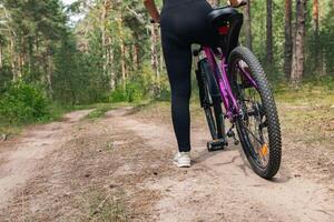Bicycle parked on a forest trail, suggesting a perfect setting for mountain biking. The trail winds through dense trees, providing a scenic and adventurous backdrop. photo