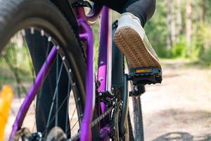 Person riding a bike on a forest trail. The bike is sturdy with thick tires, suitable for off-road biking. The rider is dressed in casual athletic gear, enjoying a ride through the wooded area. photo
