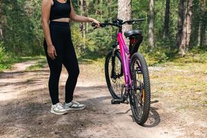 Bicycle parked on a forest trail, suggesting a perfect setting for mountain biking. The trail winds through dense trees, providing a scenic and adventurous backdrop. photo