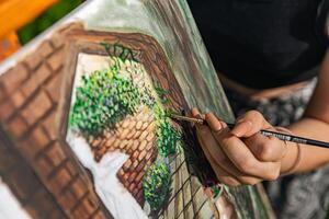 Close-up of someone skillfully painting on a canvas. The artwork looks like it depicts a rustic scene, possibly featuring elements like bricks or wood, giving it a cozy, homely feel. photo