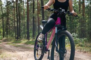Bicycle parked on a forest trail, suggesting a perfect setting for mountain biking. The trail winds through dense trees, providing a scenic and adventurous backdrop. photo
