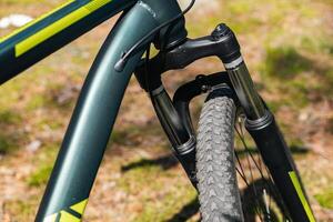 Close-up of a bicycle parked on a dirt trail, with a focus on the kickstand. The bike's rugged tires are well-suited for trail riding, and the scene suggests a forest environment. photo