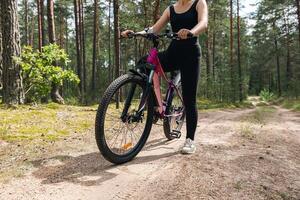 Bicycle parked on a forest trail, suggesting a perfect setting for mountain biking. The trail winds through dense trees, providing a scenic and adventurous backdrop. photo