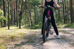 Bicycle parked on a forest trail, suggesting a perfect setting for mountain biking. The trail winds through dense trees, providing a scenic and adventurous backdrop. photo