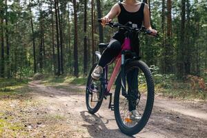 Bicycle parked on a forest trail, suggesting a perfect setting for mountain biking. The trail winds through dense trees, providing a scenic and adventurous backdrop. photo