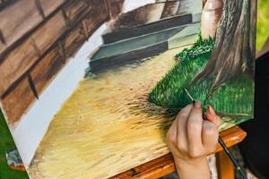 Close-up of someone skillfully painting on a canvas. The artwork looks like it depicts a rustic scene, possibly featuring elements like bricks or wood, giving it a cozy, homely feel. photo