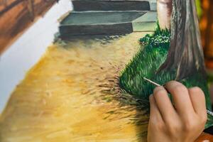 Close-up of someone skillfully painting on a canvas. The artwork looks like it depicts a rustic scene, possibly featuring elements like bricks or wood, giving it a cozy, homely feel. photo