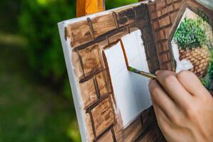 Close-up of someone skillfully painting on a canvas. The artwork looks like it depicts a rustic scene, possibly featuring elements like bricks or wood, giving it a cozy, homely feel. photo