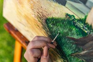 Close-up of someone skillfully painting on a canvas. The artwork looks like it depicts a rustic scene, possibly featuring elements like bricks or wood, giving it a cozy, homely feel. photo