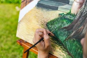 Close-up of someone skillfully painting on a canvas. The artwork looks like it depicts a rustic scene, possibly featuring elements like bricks or wood, giving it a cozy, homely feel. photo