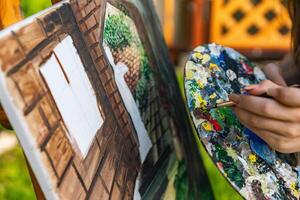 Artist in the middle of painting a picturesque scene. The painting is on an easel, and it includes elements like a tree, stair, and perhaps other architectural features. photo