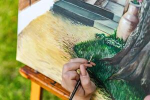 Close-up of someone skillfully painting on a canvas. The artwork looks like it depicts a rustic scene, possibly featuring elements like bricks or wood, giving it a cozy, homely feel. photo