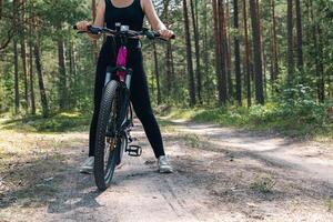Bicycle parked on a forest trail, suggesting a perfect setting for mountain biking. The trail winds through dense trees, providing a scenic and adventurous backdrop. photo