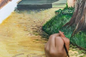 Close-up of someone skillfully painting on a canvas. The artwork looks like it depicts a rustic scene, possibly featuring elements like bricks or wood, giving it a cozy, homely feel. photo