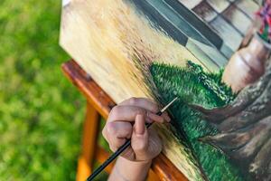 Close-up of someone skillfully painting on a canvas. The artwork looks like it depicts a rustic scene, possibly featuring elements like bricks or wood, giving it a cozy, homely feel. photo