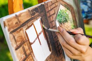 Close-up of someone skillfully painting on a canvas. The artwork looks like it depicts a rustic scene, possibly featuring elements like bricks or wood, giving it a cozy, homely feel. photo