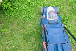 Lawn mower on a grassy lawn. Push mower with a grass collection bag attached to the back. Grass to a consistent height, providing a neat and uniform lawn appearance. photo