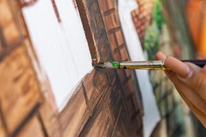 Close-up of someone skillfully painting on a canvas. The artwork looks like it depicts a rustic scene, possibly featuring elements like bricks or wood, giving it a cozy, homely feel. photo