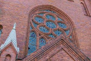 Gothic-style church, characterized by its pointed arches, tall spires, and intricate brickwork. The architecture includes large stained glass windows, likely with elaborate designs. photo