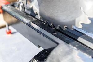 Miter saw tool blade up close for cutting lumber and carpentry. Using a circular saw to cut a wooden board. Blade of a miter saw to cut off the edge of a wooden board, close up. photo
