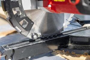 Cuts a wooden beam using a circular saw. Home furniture workshop. Work in his carpentry workshop. Miter saw and planks for building a house. photo