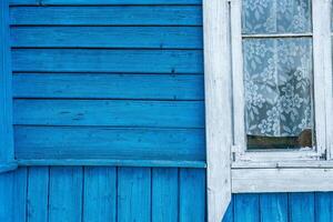 Close-up of a wooden building with windows. The building is painted in a bright, vibrant blue. The windows are framed in white, providing a stark contrast to the blue background. photo