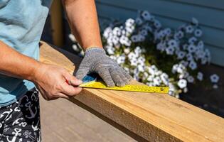 Yellow ruler placed on a wooden beam. Tools are being used to measure and mark the wooden beam for cutting or construction. The close-up view of the tools and the wooden beam. photo
