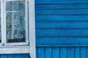 Close-up of a wooden building with windows. The building is painted in a bright, vibrant blue. The windows are framed in white, providing a stark contrast to the blue background. photo