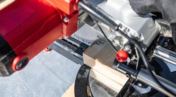 Cuts a wooden beam using a circular saw. Home furniture workshop. Work in his carpentry workshop. Miter saw and planks for building a house. photo