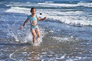 An 8 year old girl in a swimsuit having fun in the sea waves. photo