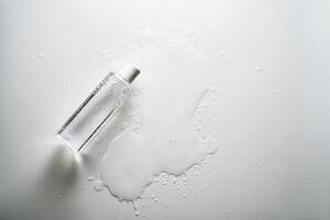 Bottle of facial toner or cleanser on white background with drops of product. photo