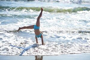 A girl does a cartwheel on the seashore. photo