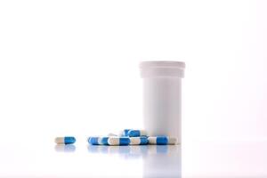 Bottle with white and blue capsules on a white background. photo