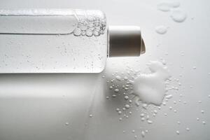 Bottle of facial toner or cleanser on white background with drops of product. photo