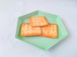 Sugar coated biscuits, also known as malkist, sweet and crispy. on a green hexagon plate isolate on white. snack concept photo