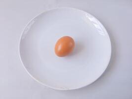 chicken egg on a round white plate isolate on white. vegan concept. protein rich food. diet menu photo