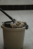 a bucket with a mop and a broom on a tile floor photo